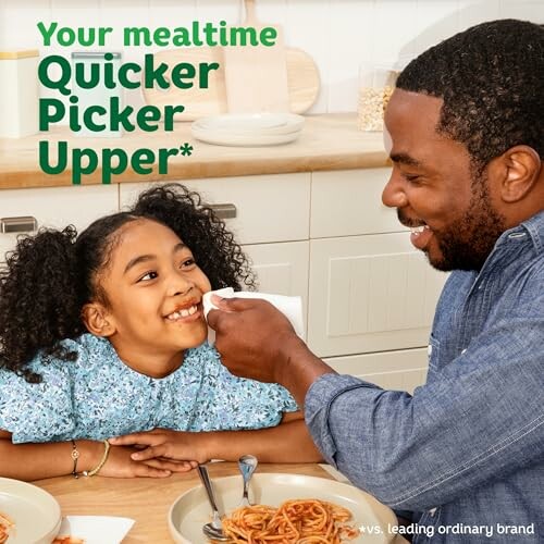 Dad wiping daughter's face at kitchen table.