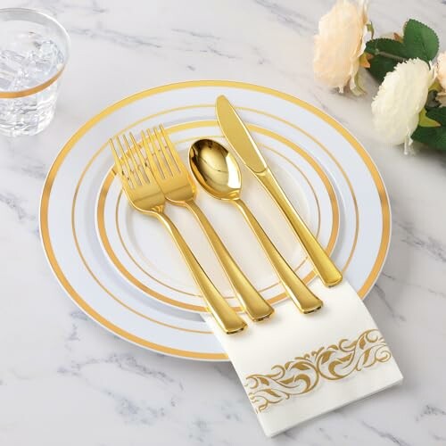 Elegant table setting with gold cutlery and decorative plates.