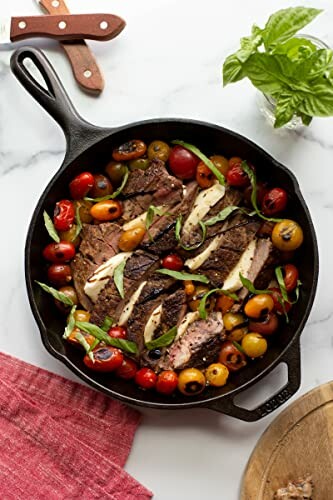Grilled steak with cherry tomatoes and herbs in a cast iron skillet.