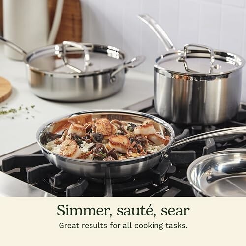 Stainless steel cookware set on stove with sautéed food.
